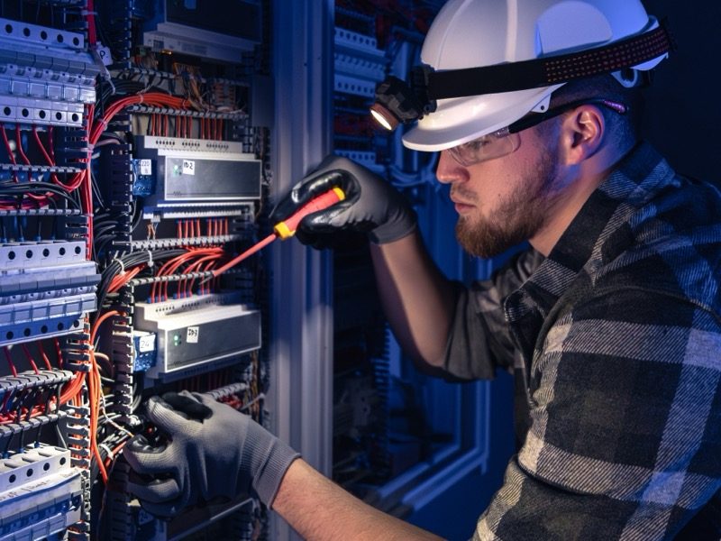 Techniker prüft eine Verteilung mit Stirnlampe
